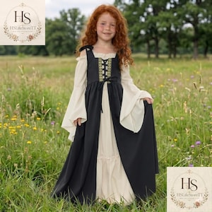 May include: A floor-length dress featuring a cream-coloured base with long, flared sleeves and an off-the-shoulder neckline. A black bodice overlay with a central lace-up panel and decorative gold-toned trim sits over the cream-coloured skirt.