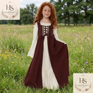 May include: A floor-length dress featuring a cream-coloured under-layer with long bell sleeves and a dark maroon over-layer. The over-layer has a corset-style bodice with a decorative gold and black trim, a lace-up front, and shoulder straps.