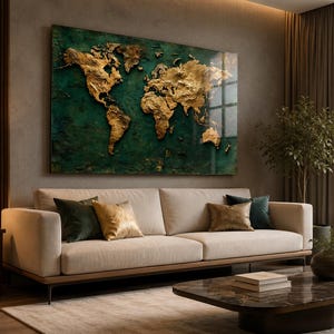 Puede incluir: Una gran obra de arte de un mapa del mundo dorado cuelga sobre un sofá beige. El mapa está sobre un fondo verde oscuro. Cojines decorativos en tonos dorados, verdes y marrones adornan el sofá. Una mesa de centro y una planta en maceta completan la habitación.