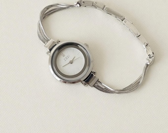 Reloj de pulsera de cuarzo para mujer con caja redonda de oro y plata y brazalete ornamentado con cuentas.