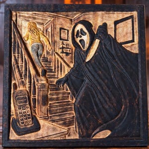 May include: A square wall plaque featuring a relief carving of a hooded figure in a ghost mask holding a knife, a person running up a staircase, and a cordless telephone on a base. The scene is rendered in shades of black and metallic gold.