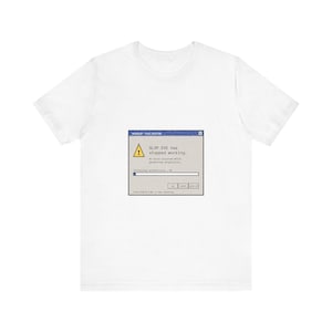 Może przedstawiać: Biały t-shirt z krótkim rękawem z centralną grafiką przedstawiającą okno błędu komputera. Okno zawiera tekst SLOP.EXE has stopped working, an error occurred while generating originality oraz pasek postępu z napisem Installing authenticity.