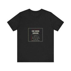 Puede incluir: Una camiseta negra de manga corta con un gráfico rectangular blanco con el texto VIBE CODING SURVIVOR, seguido de una lista de verificación con los elementos SHIPPED IT, NO TESTS, NO DOCS, WORKS ON MY MACHINE y NO IDEA HOW, con marcas rojas.