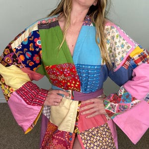May include: A long, patchwork robe with a V-neck and long sleeves. The robe is made of various colorful fabrics with floral and geometric patterns.
