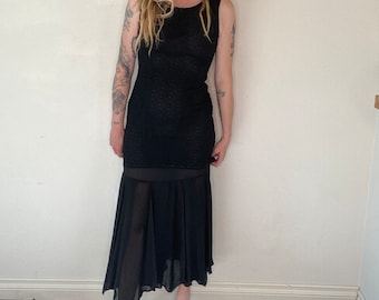 May include: A black sleeveless maxi dress with a sheer overlay skirt. The dress has a fitted bodice and a flowing skirt.