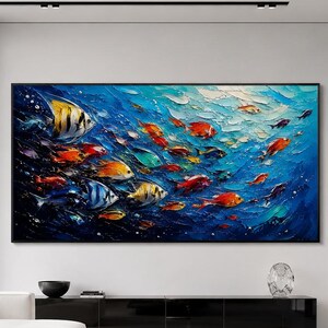 May include: A large rectangular wall art piece featuring an oil painting of a school of tropical fish swimming through deep blue water. The artwork displays thick, textured brushstrokes in shades of blue, orange, yellow, and white.