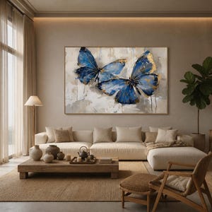 May include: A large rectangular wall art piece featuring two prominent butterflies painted in shades of deep blue and gold leaf accents against a textured, neutral-toned background with visible brushstrokes and vertical paint drips.