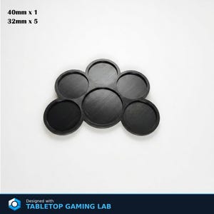 Puede incluir: Base negra para juegos de mesa con seis ranuras circulares. El texto de la imagen dice "40mm x 1" y "32mm x 5". Dise&ntilde;ado con TABLETOP GAMING LAB.