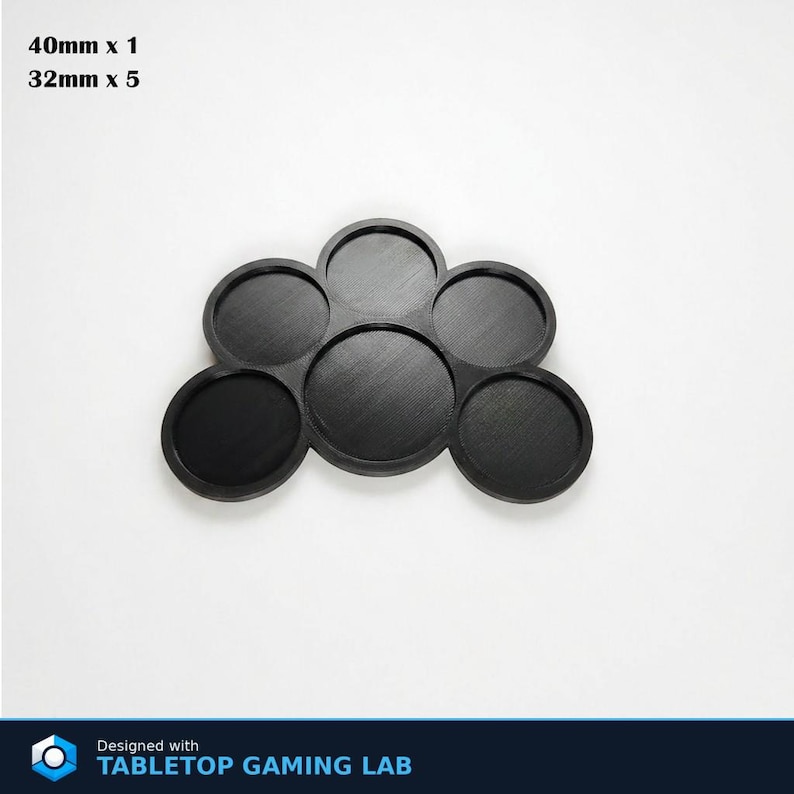 Puede incluir: Base negra para juegos de mesa con seis ranuras circulares. El texto de la imagen dice "40mm x 1" y "32mm x 5". Dise&ntilde;ado con TABLETOP GAMING LAB.