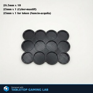 Puede incluir: Base de juego de mesa de pl&aacute;stico negro con 12 ranuras circulares. La base est&aacute; dise&ntilde;ada para contener miniaturas y fichas. El texto de la imagen dice: 28,5 mm x 10, 25 mm x 1 (Cyber-mastiff), 25 mm x 1 para ficha (Nuncio-acquila). Dise&ntilde;ado con TABLETOP GAMING LAB.