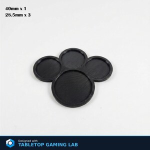 Puede incluir: Bases negras y circulares para juegos de mesa. Una base tiene 40 mm de di&aacute;metro y tres tienen 28,5 mm. Las bases est&aacute;n dispuestas en forma de tr&eacute;bol de cuatro hojas. El texto "40mm x 1" y "28.5mm x 3" es visible.