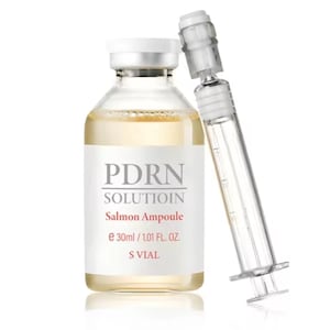May include: A clear glass bottle with a white cap and label, containing a yellow liquid. The label reads "PDRN SOLUTION Salmon Ampoule e 30ml / 1.01 FL. OZ. S VIAL." A clear syringe is positioned next to the bottle.