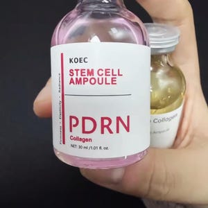May include: A pink-tinted glass vial labeled "KOEC STEM CELL AMPOULE PDRN Collagen" with a net volume of 30 ml / 1.01 fl. oz. The vial is held next to a smaller vial with a white label that reads "Collagen Ampoule".