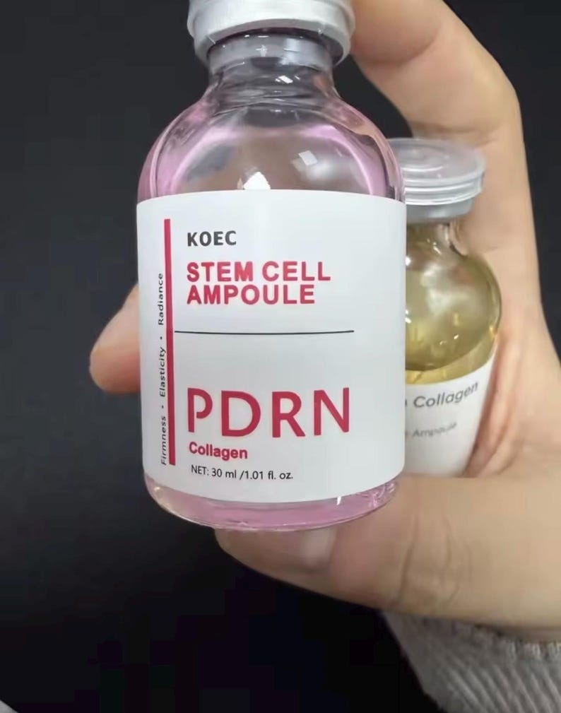 May include: A clear glass bottle with a pink liquid inside, labeled "KOEC STEM CELL AMPOULE PDRN Collagen." The bottle contains 30 ml / 1.01 fl. oz. of product. The bottle is held in a hand.