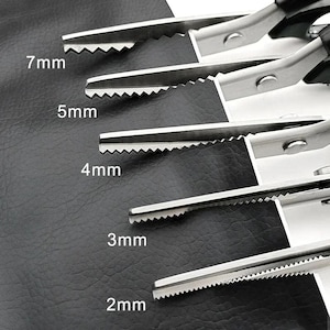 May include: A set of five silver metal pinking shears with black handles, each featuring a distinct serrated blade edge. The blades are labeled with specific cutting sizes of 7mm, 5mm, 4mm, 3mm, and 2mm, indicating the width of the zigzag cut.