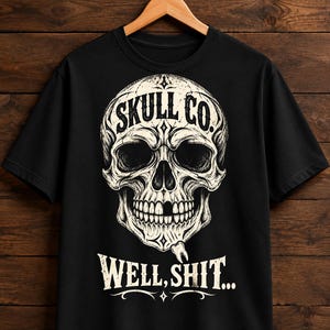 May include: A black short-sleeve t-shirt featuring a large, detailed off-white graphic of a human skull with a missing tooth. Above the skull is the text "SKULL CO." and below the skull is the text "WELL, SHIT..." in a distressed, bold font.