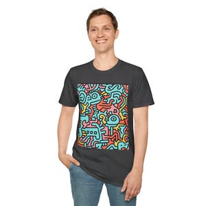 Puede incluir: Camiseta gris oscuro con un diseño abstracto colorido. El gráfico incluye formas en rojo, amarillo, azul y rosa. La camiseta está hecha de un material suave y tiene cuello redondo.