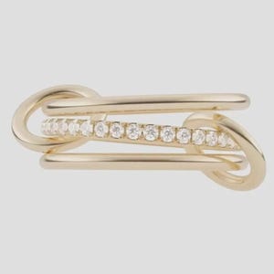 May include: A gold ring featuring a multi-band design with two smooth, polished gold bands flanking a central band embedded with a row of small, clear, round-cut stones. The bands are connected by two oval-shaped gold links on each side.