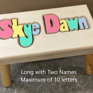 Step stool with four legs that has the name Skye Dawn puzzled into the top where each letter is a puzzle piece.  Letters are painted in bright pastel colors in a rainbow pattern starting with pink.  2 name size holds 2 name up to 10 letters maximum.