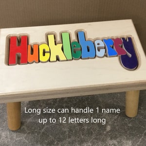 Step stool with four legs that has the name Huckleberry puzzled into the top where each letter is a puzzle piece.  Letters are painted in bright primary colors in a rainbow pattern starting with red.  Long size holds 1 name up to 12 letters maximum.