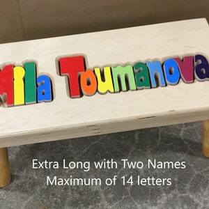 Step stool with 4 legs that has the name Mila Toumanova puzzled into the top where each letter is a puzzle piece.  Letters are painted in primary colors in a rainbow pattern starting with red.  2 name size holds 2 names with up to 14 letters maximum.