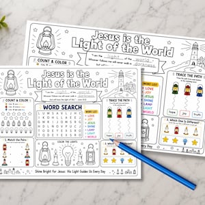 May include: Two white activity sheets with the text "Jesus is the Light of the World" and various activities. The sheets include a word search, coloring sections, and matching games. A blue pencil rests on the sheets. The theme is religious education.