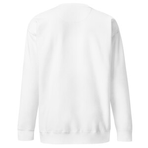 Peut inclure: Un sweat-shirt blanc à manches longues doté d'un col rond classique, de poignets côtelés aux extrémités des manches et d'un ourlet côtelé. Le vêtement est fabriqué dans un tissu blanc uni avec une texture lisse et une coupe standard.