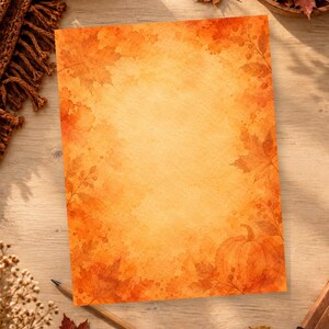 Puede incluir: Una hoja de papel rectangular con una ilustración en acuarela de hojas de otoño, bayas y una calabaza en los bordes. El centro del papel es de un tono amarillo cálido más claro, mientras que los bordes se transforman en tonos naranja y rojo.