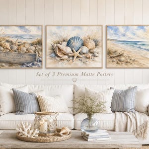 Könnte beinhalten: Ein Set aus drei rechteckigen, matten Postern mit Aquarellillustrationen von Küstenszenen. Die Bilder zeigen Muscheln, eine Holzkiste und einen Sandstrand mit Meereswellen. Jeder Druck ist in einem hellen Holzrahmen eingefasst.