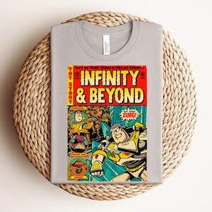 Puede incluir: Una camiseta gris claro con un estampado gr&aacute;fico colorido dise&ntilde;ado como una portada de c&oacute;mic vintage. El texto dice Toy Story Infinity & Beyond, con ilustraciones de Buzz Lightyear, Emperor Zurg y un Zurgbot en marcos circulares.