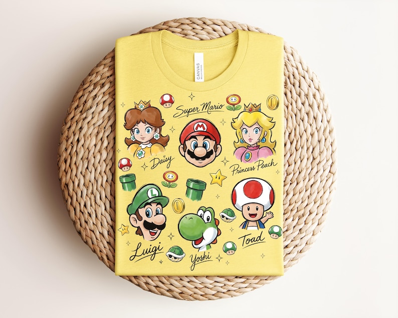 May include: Yellow t-shirt featuring cartoon illustrations of Super Mario characters, including Mario, Luigi, Princess Peach, and Yoshi. The text "Super Mario" and character names are also printed on the shirt.