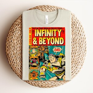 Puede incluir: Una camiseta de color beige claro con un gr&aacute;fico colorido de estilo c&oacute;mic en la parte delantera. El gr&aacute;fico muestra el texto "Toy Story" e "Infinity & Beyond" con ilustraciones de Buzz Lightyear, el Emperador Zurg y un Zurgbot.