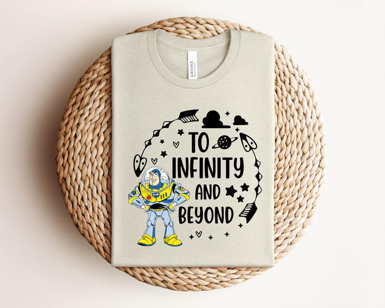 Puede incluir: Una camiseta de color beige claro con un gr&aacute;fico de un personaje de guardi&aacute;n espacial con traje blanco, azul y amarillo. El texto "TO INFINITY AND BEYOND" aparece en negro, rodeado de ilustraciones negras de flechas, estrellas, corazones y un planeta.