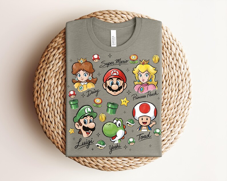 May include: A gray t-shirt featuring Super Mario characters: Mario, Luigi, Princess Peach, Daisy, Yoshi, and Toad. The shirt includes the words "Super Mario", "Daisy", "Luigi", "Princess Peach", "Yoshi", and "Toad". The design includes stars, coins, and mushrooms.