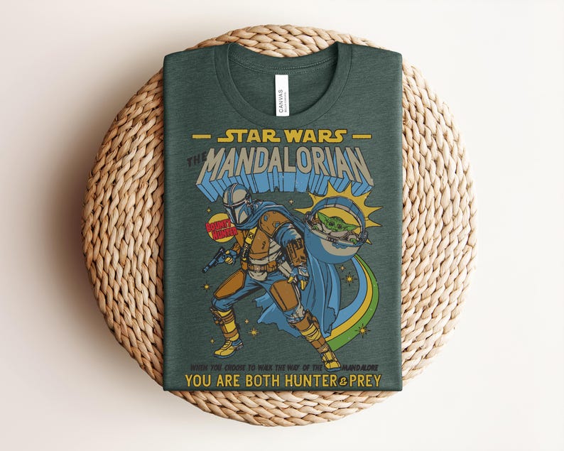 Puede incluir: Una camiseta verde oscuro con un gr&aacute;fico de The Mandalorian y Grogu. El texto dice STAR WARS THE MANDALORIAN, BOUNTY HUNTER y WHEN YOU CHOOSE TO WALK THE WAY OF THE MANDALORE YOU ARE BOTH HUNTER & PREY. El dise&ntilde;o incluye colores amarillo y azul.