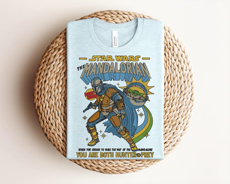 Puede incluir: Una camiseta azul claro con un gr&aacute;fico de The Mandalorian y Grogu. El dise&ntilde;o incluye el texto Star Wars The Mandalorian, Don't Hunt, y When You Choose To Walk The Way Of The Mandalore You Are Both Hunter And Prey en amarillo y azul.