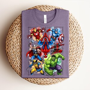 May include: A purple t-shirt with a graphic of Marvel superheroes such as Iron Man, Captain America, Spider-Man, Thor, Wolverine, Deadpool, and the Hulk. The shirt is folded on a woven, circular surface.