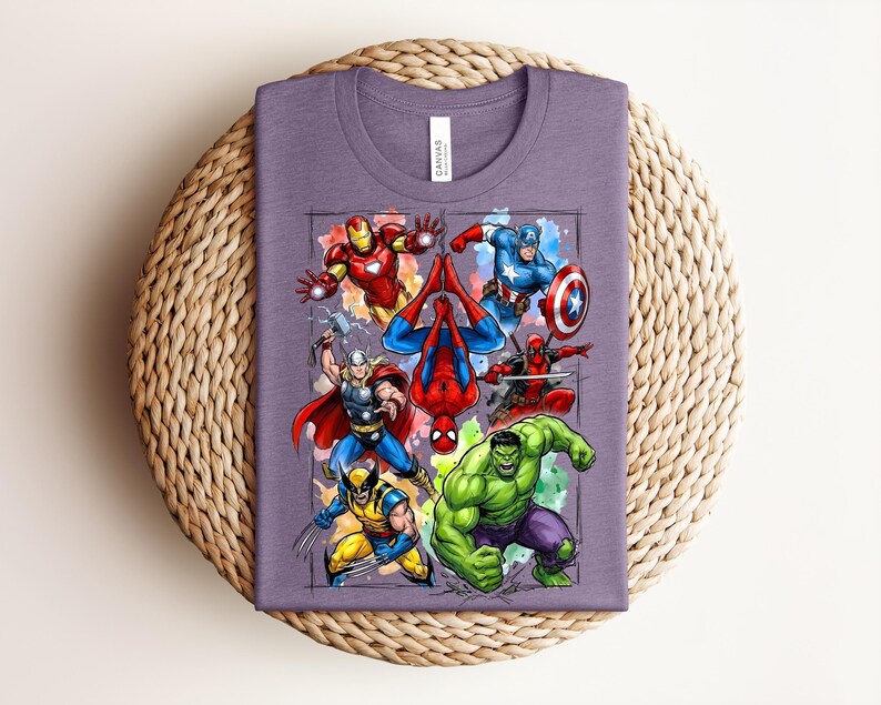 May include: A purple t-shirt with a graphic of Marvel superheroes such as Iron Man, Captain America, Spider-Man, Thor, Wolverine, Deadpool, and the Hulk. The shirt is folded on a woven, circular surface.