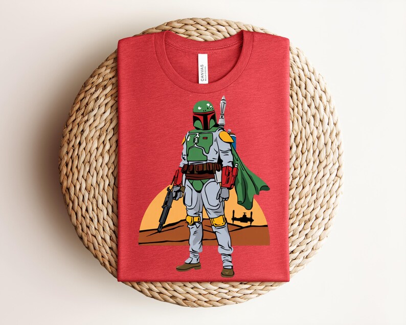 May include: Red t-shirt featuring a graphic of a character in green and gray armor, holding a weapon, with a green cape. The design includes a sunset and a spaceship silhouette.