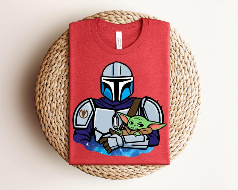 Puede incluir: Camiseta roja con una ilustraci&oacute;n de dibujos animados de un personaje mandaloriano sosteniendo a un personaje Grogu. El mandaloriano lleva un casco y una armadura, y Grogu es verde con orejas grandes. El dise&ntilde;o est&aacute; sobre un fondo espacial azul y morado.