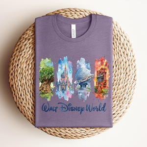 May include: A purple t-shirt featuring watercolor illustrations of iconic Walt Disney World landmarks: the Tree of Life, Cinderella Castle, Spaceship Earth, and the Tower of Terror. The words "Walt Disney World" are written in a script font below the images.