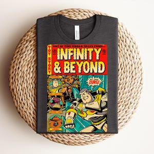 Puede incluir: Una camiseta gris oscuro de cuello redondo con un estampado gr&aacute;fico estilo c&oacute;mic. El dise&ntilde;o muestra el texto Infinity & Beyond, Toy Story y Not Today Zurg, con ilustraciones de Buzz Lightyear, Emperor Zurg y un personaje Zurgbot.