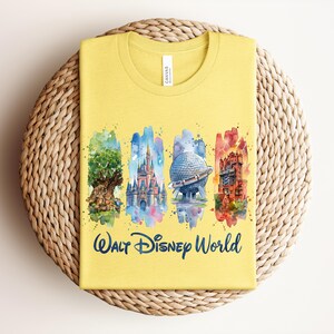 May include: Yellow t-shirt featuring watercolor illustrations of iconic Walt Disney World landmarks: the Tree of Life, Cinderella Castle, Spaceship Earth, and the Tower of Terror. The words "Walt Disney World" are printed in navy blue below the images.