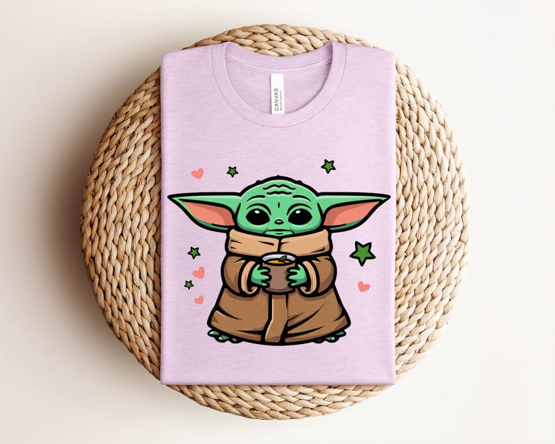 May include: A light purple t-shirt featuring a cartoon character with large green ears, holding a brown cup. The character is wearing a brown coat and a tan scarf. Green stars and pink hearts are scattered around the character.
