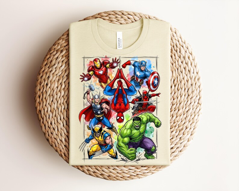May include: A beige t-shirt with a vibrant graphic of Marvel superheroes, such as Iron Man, Captain America, Spider-Man, Thor, Wolverine, Hulk, and Deadpool. The design is framed with a watercolour effect.