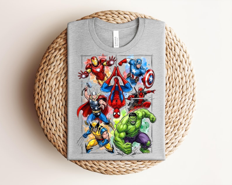 May include: A grey t-shirt with a vibrant graphic of Marvel superheroes, such as Iron Man, Captain America, Spider-Man, Thor, Wolverine, Hulk, and Deadpool. The design is set against a watercolour-style background.