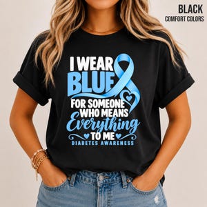 May include: A black short-sleeve t-shirt featuring the text I WEAR BLUE FOR SOMEONE WHO MEANS Everything TO ME DIABETES AWARENESS in white and light blue lettering, accompanied by a light blue awareness ribbon graphic on the front.