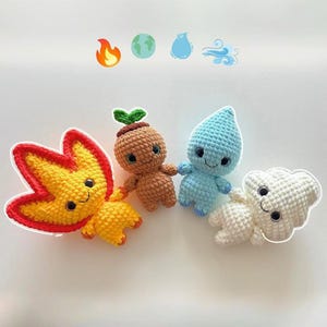 May include: Four crocheted elemental figures: fire, earth, water, and air. The fire figure is yellow and red, the earth figure is brown, the water figure is blue, and the air figure is white. Each figure has a smiling face and is holding hands.