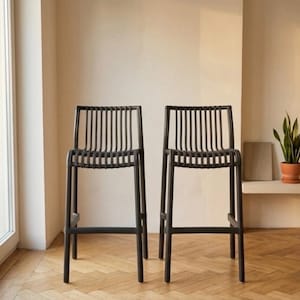 Pode incluir: Dois bancos de bar cinza-carvão escuro com um design de encosto de ripas verticais e um assento de ripas correspondente. Cada banco é construído com quatro pernas retas e barras de suporte horizontais em todos os lados para estabilidade.