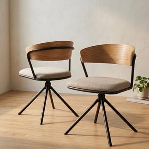 May include: Two contemporary swivel chairs. Each chair features a light wood backrest and seat, supported by a black metal frame and a tripod base. The seats are upholstered in a neutral fabric. The chairs are designed for comfort and style, suitable for a home office.